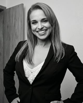 Professional black and white portrait of a smiling woman wearing a black blazer and white top